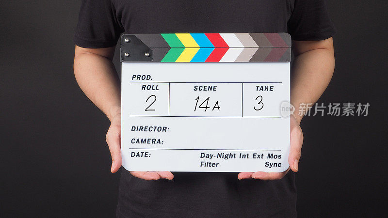 一个男人正双手捧着板书板或电影石板，上面写着数字。它是黑色的背景。