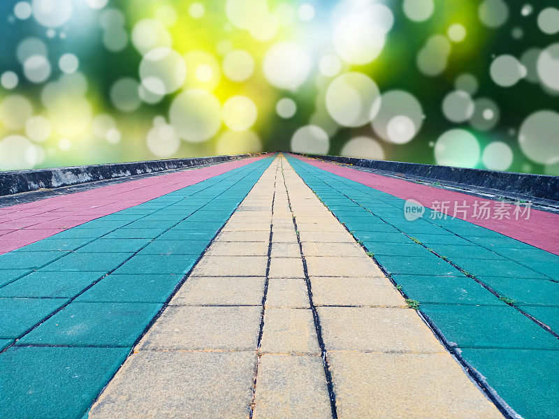 彩色的鹅卵石砖地面作为慢跑的路径在公园，以聚光灯散焦为背景。目标概念。
