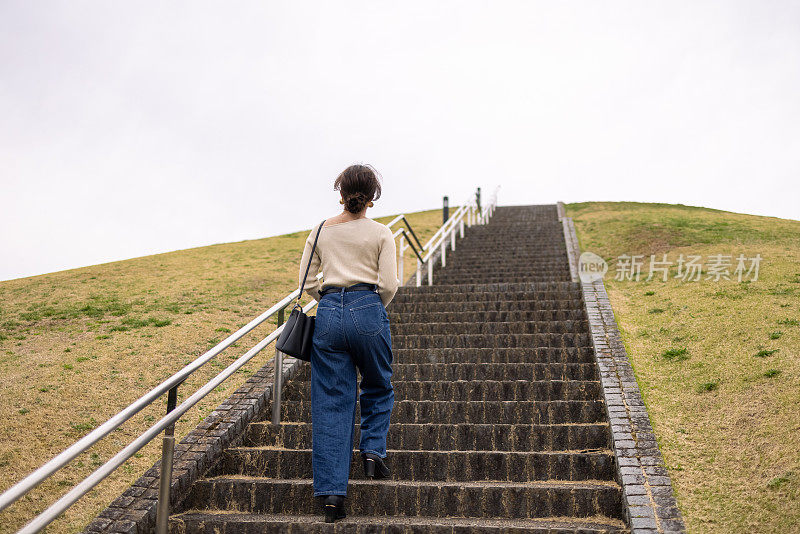 一个年轻女子在公园里走上楼梯