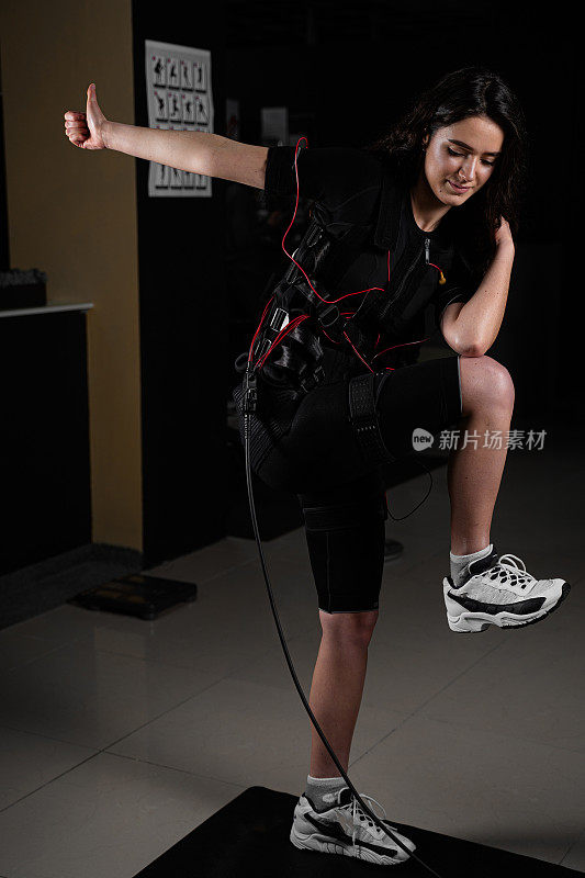 健身房里穿着急救服的女孩，穿着肌肉电刺激服进行运动训练。