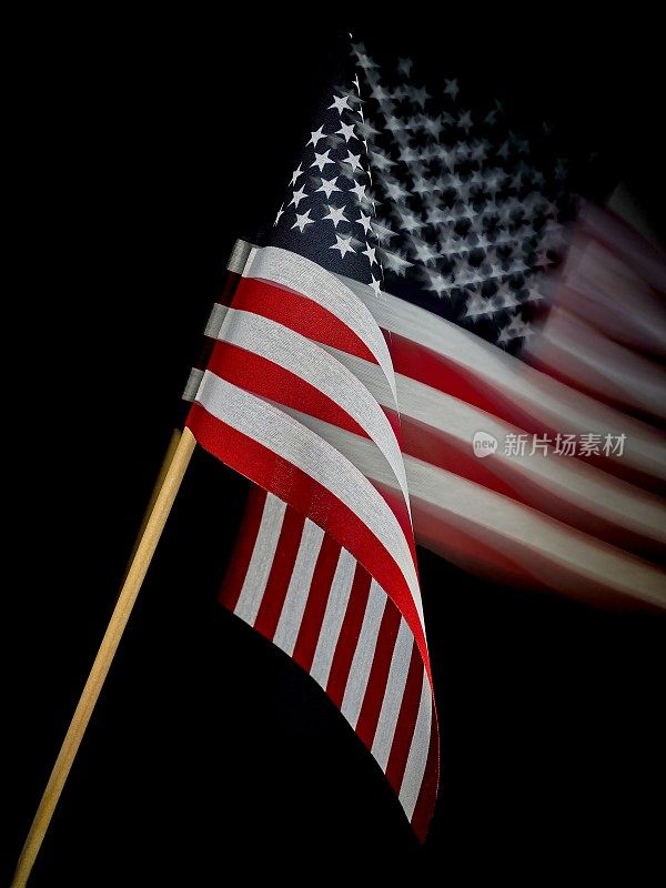 黑色背景的木制旗杆的美国国旗在微风中飘扬
