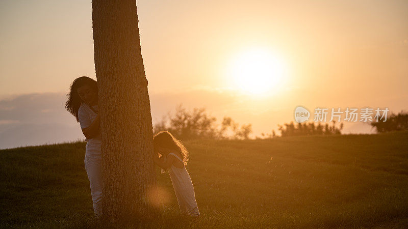 日落时分，女孩和妈妈在公园里玩捉迷藏