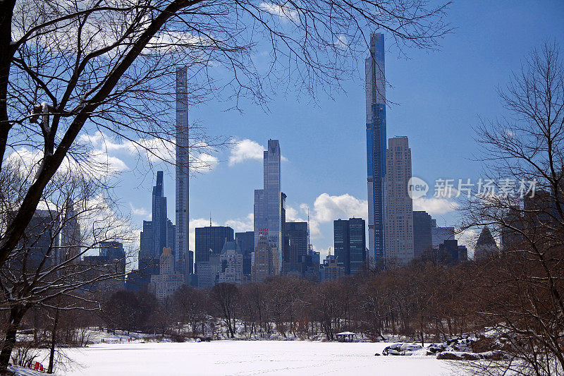 亿万富翁的摩天大楼在纽约中央公园的雪湖后面排着