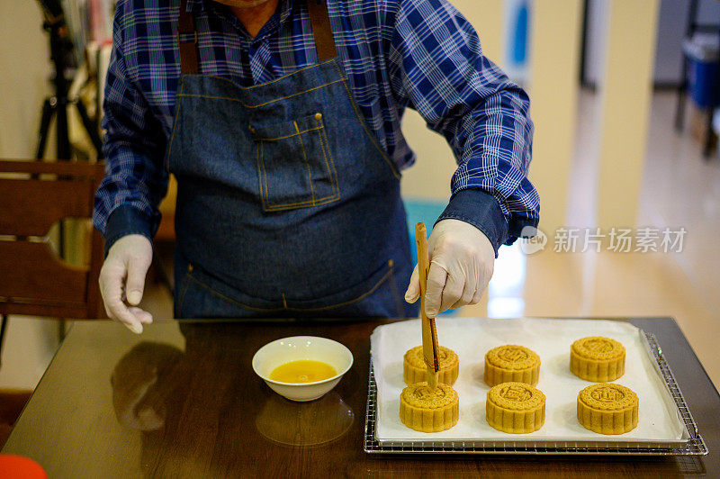 面包师在烤盘上用鸡蛋面团画自制月饼