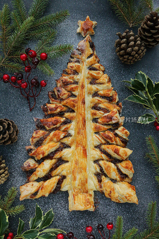 圣诞树形状的节日糕点甜点形象，酥脆的糕点充满了甜的肉馅(混合切碎的干果，蒸馏酒，香料)，洒上糖粉，高高在上
