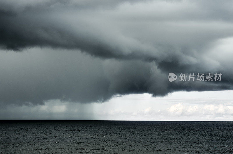 戏剧性的多云下雨的天空在黑暗的水面海