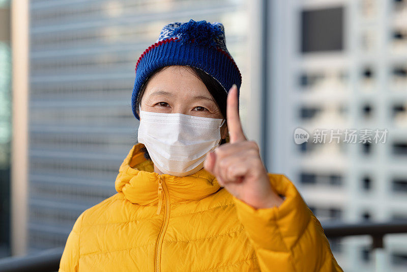 戴口罩的女人举起一根手指