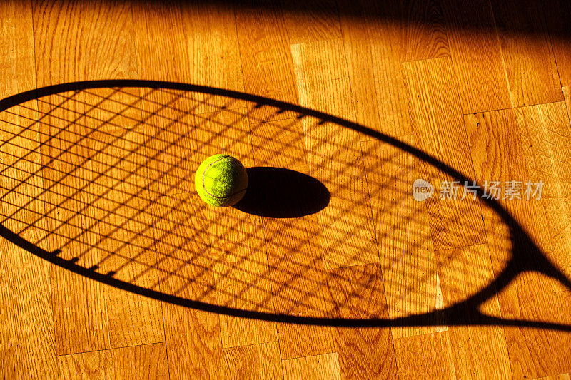 看到一个网球和网球拍在地板上的影子。背景运动主题
