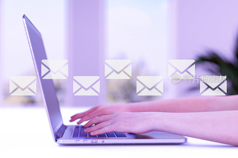 电子邮件图标，电子邮件营销和时事通讯的概念，在办公室或家里使用她的笔记本电脑的女人