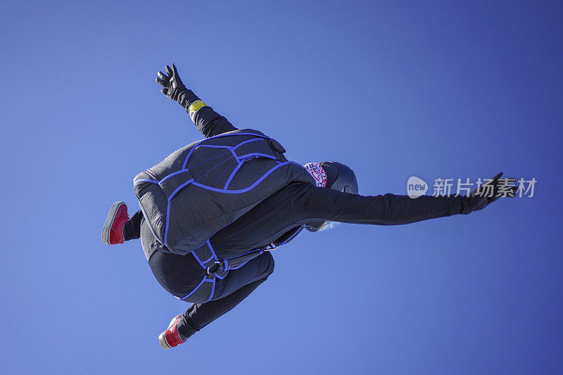 女跳伞运动员穿过晴空万里，在空中飞行