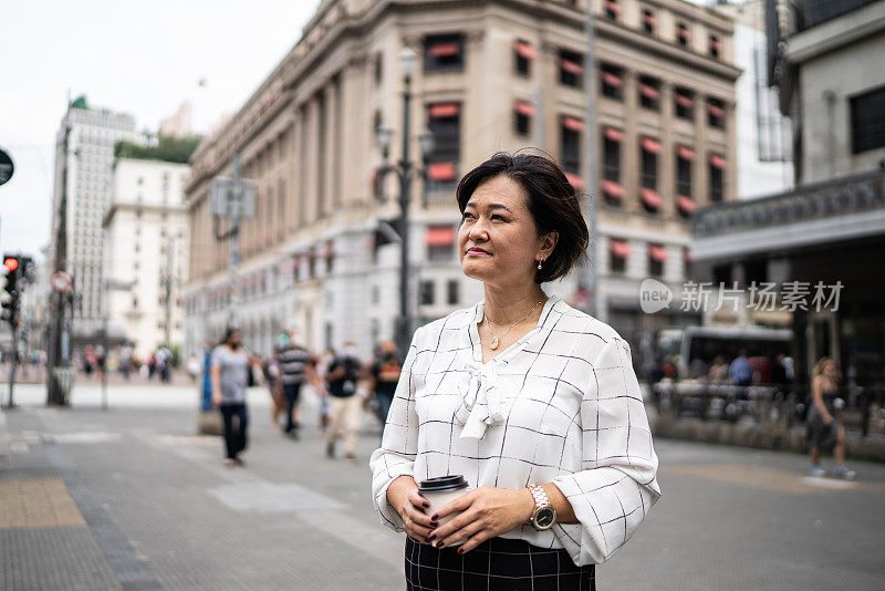 沉思成熟的亚洲女商人，在城市中望向别处