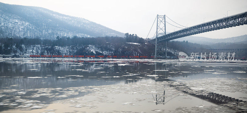 在冬天，一列货运火车行驶在结冰的河边
