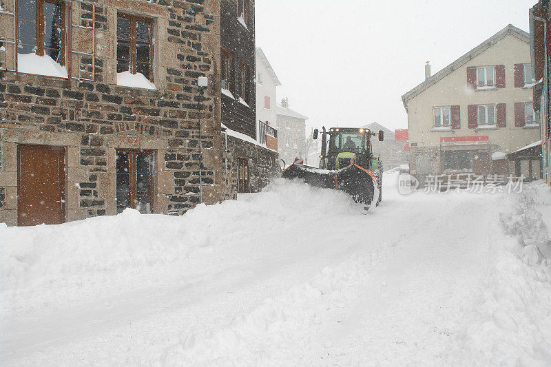 在一个小村庄里，铲雪机在积雪的街道上忙碌