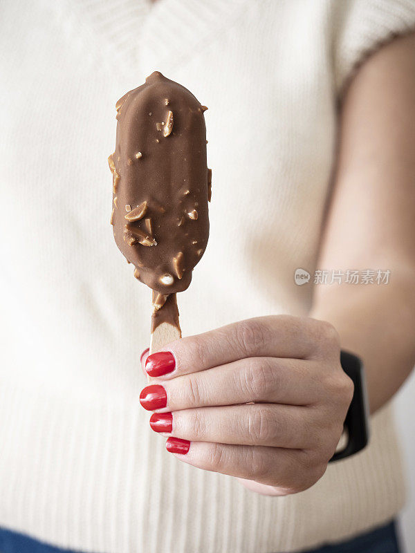 棒状冰淇淋，女人手拿巧克力冰淇淋，手拿巧克力杏仁冰淇淋棒