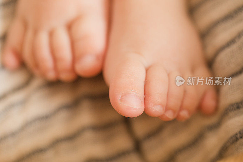 一个21周大的男婴的脚有12个脚趾，躺在舒适的纱布棉毯上，在海草摩西篮子里