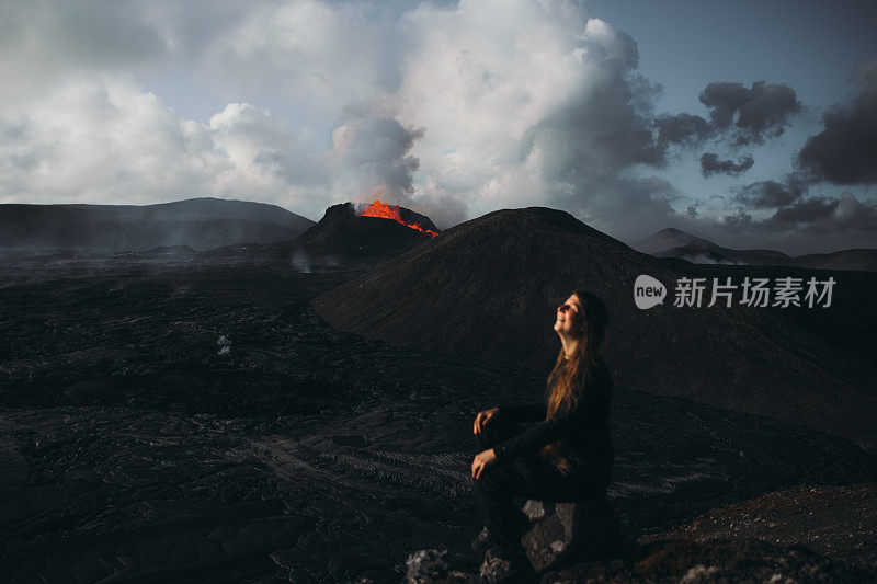 年轻的女游客在冰岛Fagradalsfjall火山喷发的戏剧性的观点