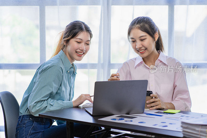 两名年轻的亚洲女性在创业时讨论投资项目和规划策略。商人在办公室用手提电脑交谈