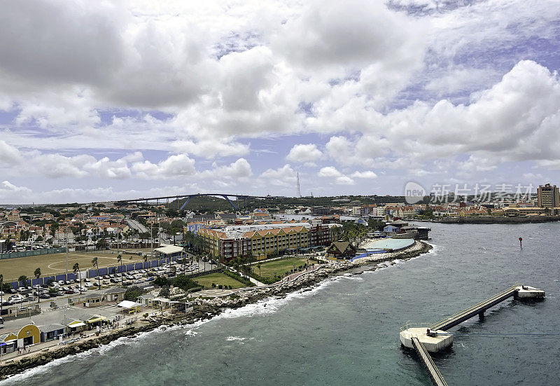 乘坐游轮抵达威廉斯塔德，Curaçao(荷兰王国的一部分)的首都，我们看到邮轮码头欢迎中心，码头扩建，酒店和公寓，一个球场，以及著名的朱莉安娜女王桥