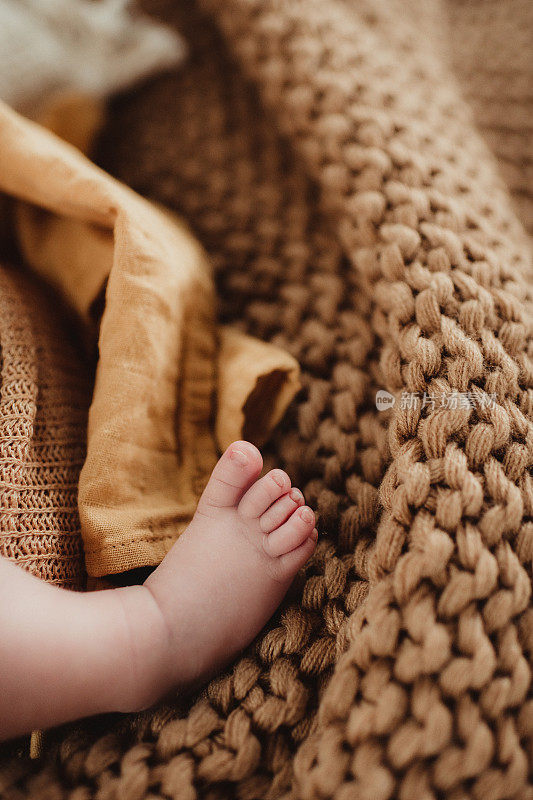 刚出生的婴儿脚踩在黄色的毯子上