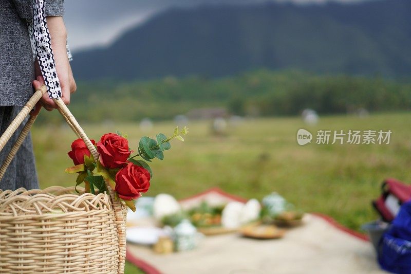 后院的篮子里，女人手拿红玫瑰