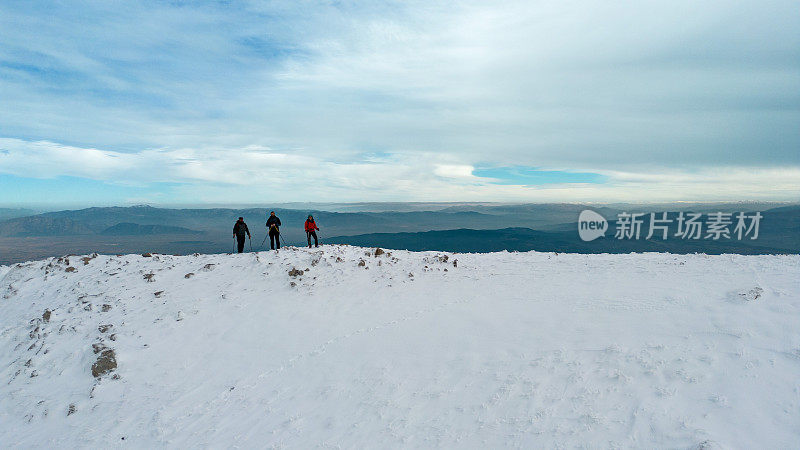 冬季，在雪山峰顶的山脊上，成功的登山队正对着相机排成一排