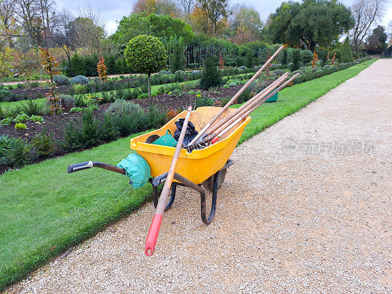秋天的一天，园丁们把装满园艺工具的手推车放在正规花园的小路上，为冬天做准备。