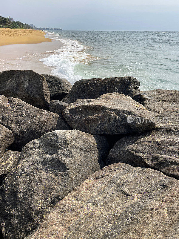 斯里兰卡海岸线上的岩石天然海防特写图像，海岸侵蚀抛石岩甲墙，海岸管理，岩石堆，沙滩，岩甲，海浪，斯里兰卡科伦坡