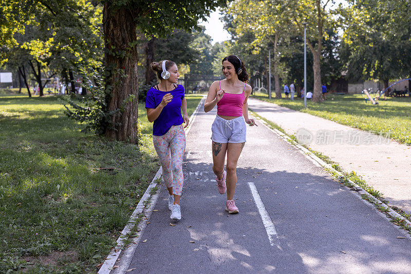 两个女性朋友一起在跑道上跑步