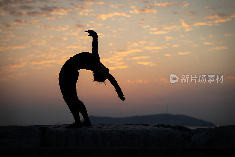 夕阳下柔韧的年轻女子剪影。