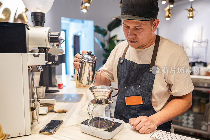 一名亚洲咖啡馆工作人员正在为上班的顾客准备咖啡