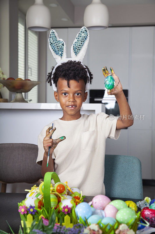 一个非裔美国男孩在厨房里装饰复活节彩蛋