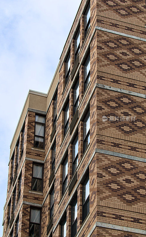 高大的砖砌公寓建筑，有着丰富多彩的华丽细节(楼上的窗户与蓝色多云的天空)新泽西州泽西城的高层住宅楼(历史房地产)