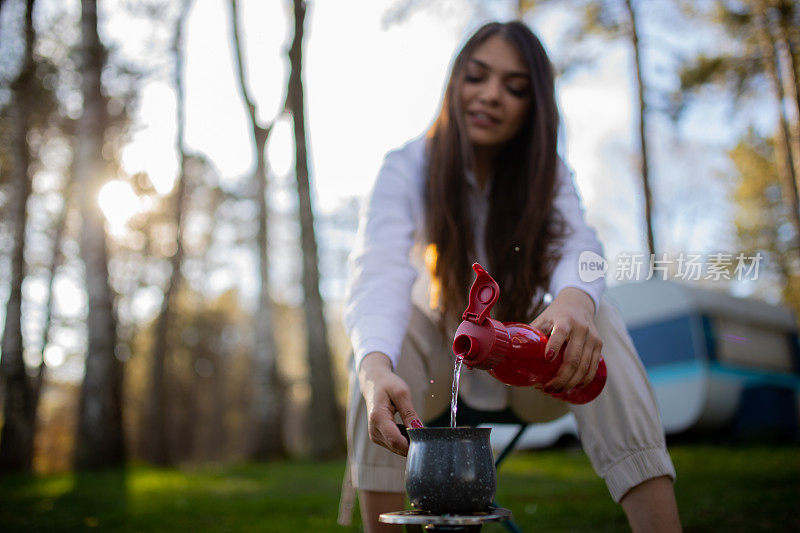 年轻女子在大自然中的露营炉上煮咖啡