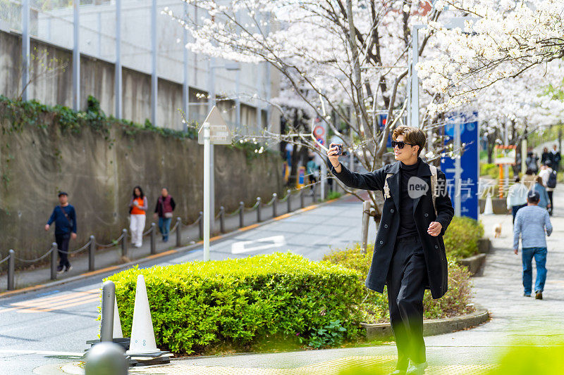 一名亚洲男子在日本东京旅行时用手机自拍。