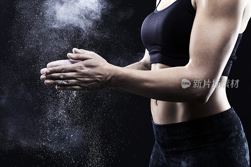 肌肉发达的女人用粉笔在手上握力