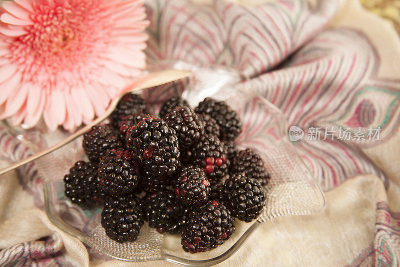 新鲜的黑莓水果在一个碗与花。