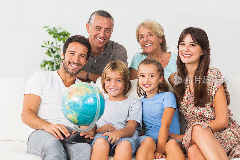 微笑的家人在沙发上和地球仪