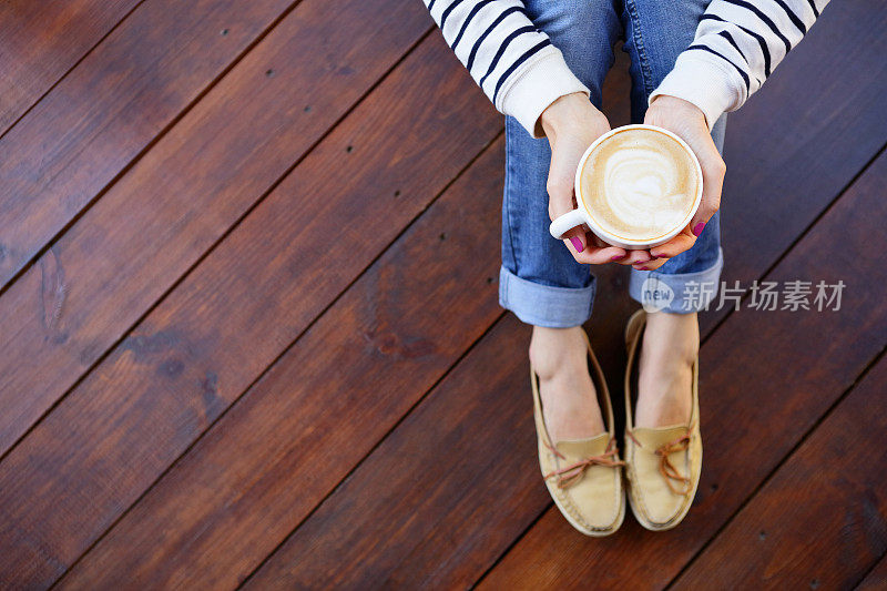 手里拿着咖啡的女人坐在地板上