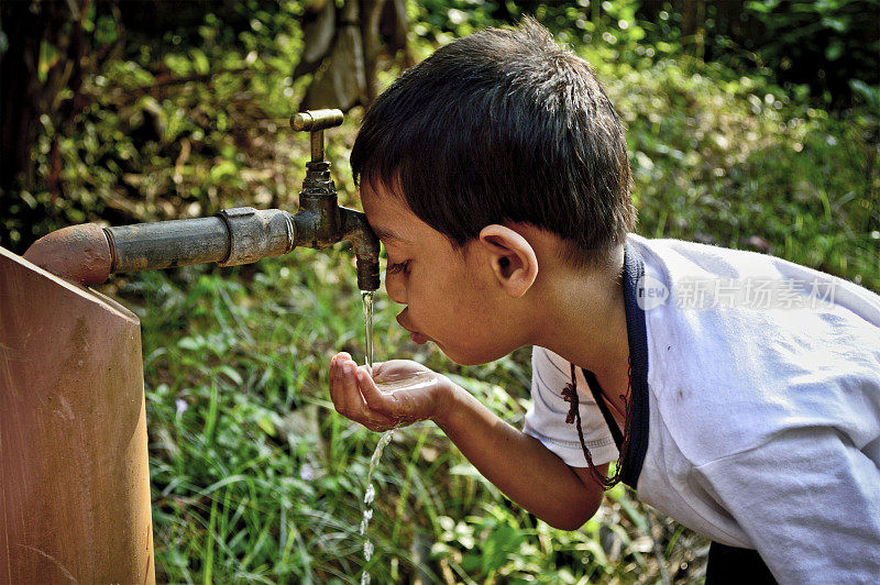 一名五岁印度男孩在喝路边水龙头里的水