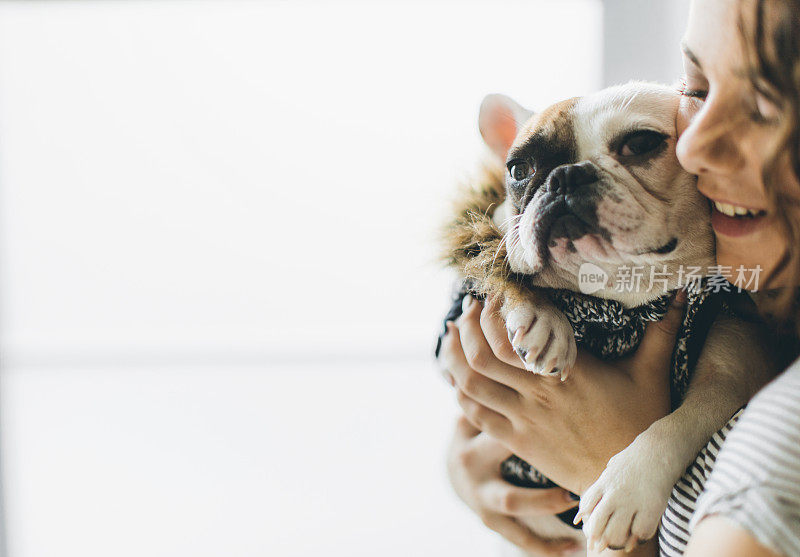 一个自信的女人抱着一只法国斗牛犬