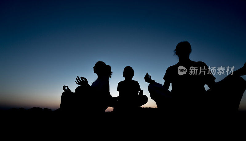 夕阳下一家人做瑜伽的剪影