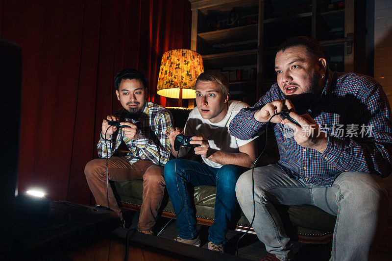 三个精神高度集中的年轻人玩电子游戏