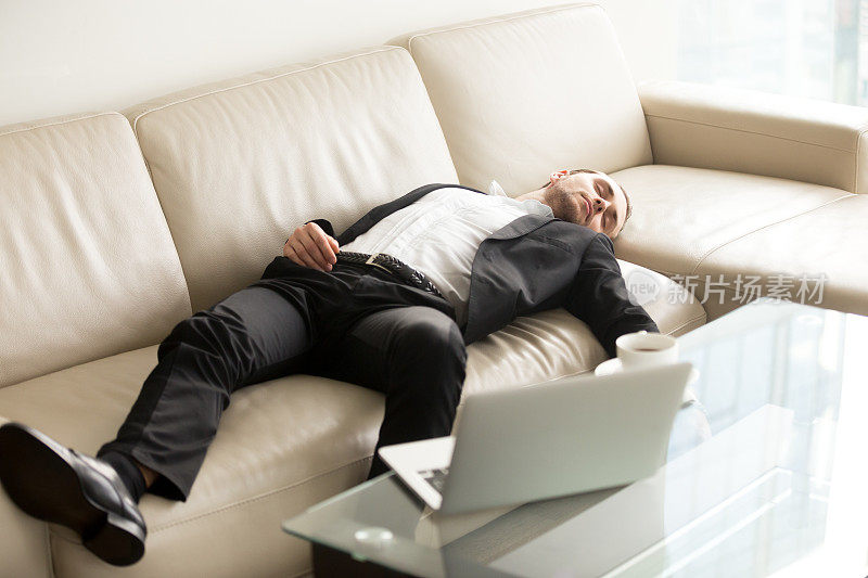 疲惫的商人睡在办公室的沙发上
