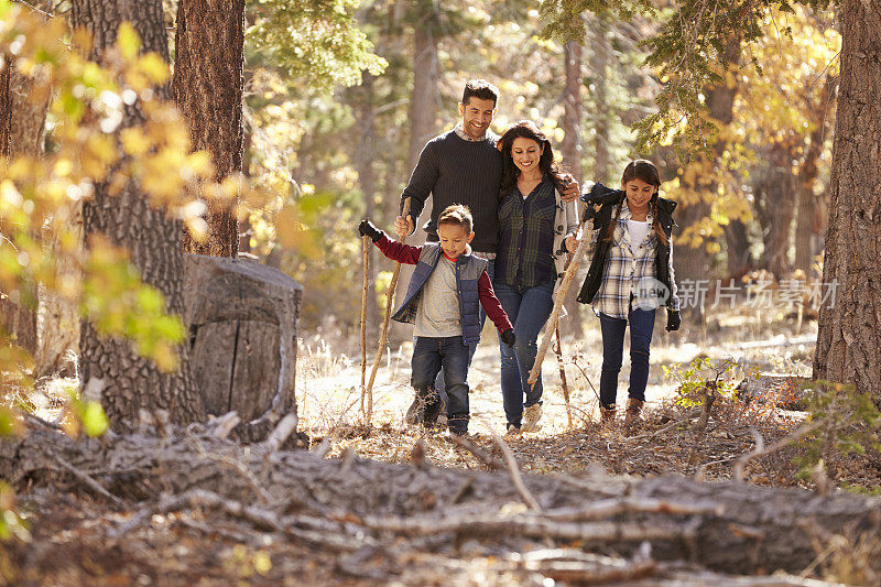 一个幸福的西班牙家庭带着两个孩子在森林里散步