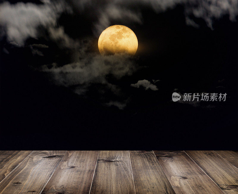 万圣节的背景。木桌上的满月和夜晚的云。