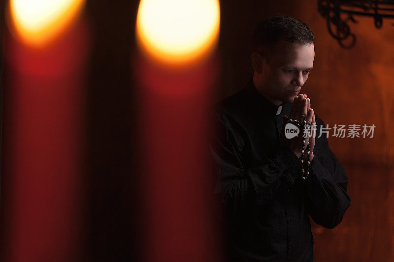 牧师祷告。牧师的肖像在蜡烛旁祈祷
