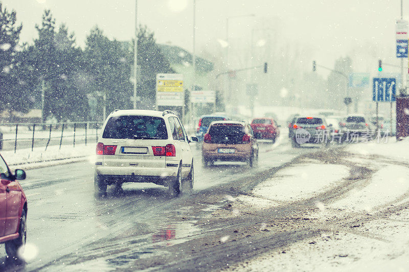 暴风雪在道路上能见度很低，车辆在十字路口亮着灯