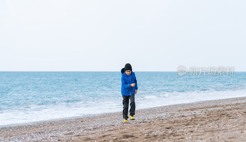 快乐男孩在一个冬日的海滩上慢跑