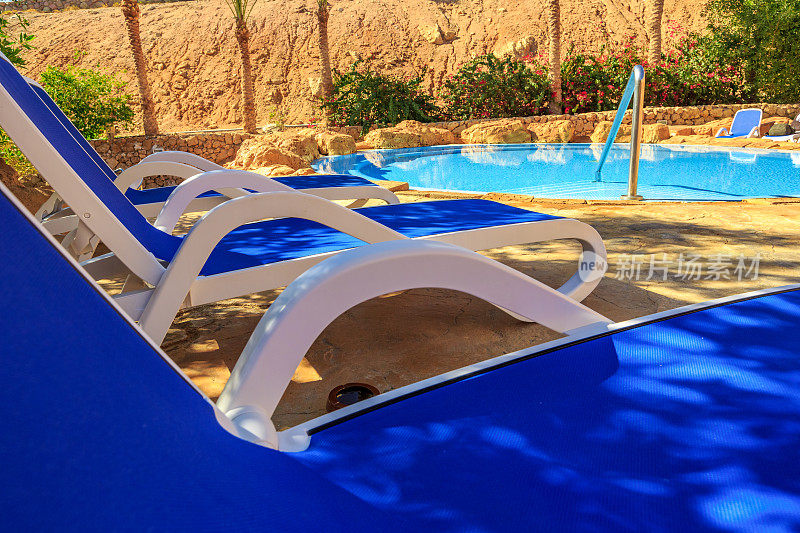 特写几个太阳躺椅在一个美丽的游泳池。