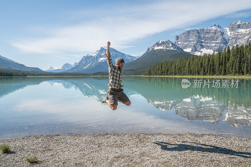 一个年轻人在山上的湖边半空中跳着